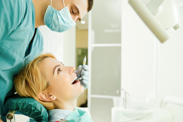 Dentist looking the teeth of the patient girl