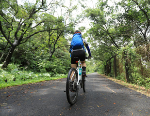 Woman cyclist riding mountain bike on tropical rainforest trail