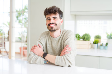 Handsome young man smiling cheerful at the camera with crossed arms and a big smile on face showing teeth