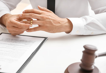 Man taking wedding ring off his finger at lawyer's office. Concept of divorce