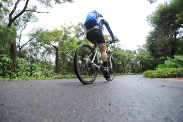 Fototapeta premium Woman cyclist riding mountain bike on tropical rainforest trail