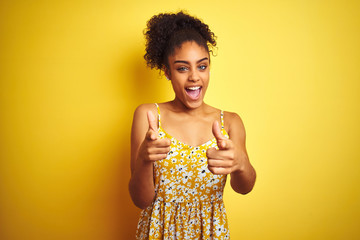 African american woman wearing casual floral dress standing over isolated yellow background...