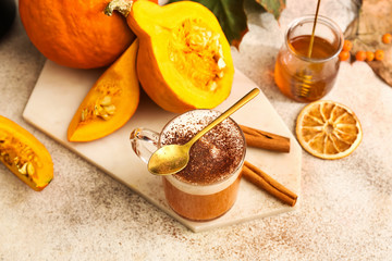 Cup of tasty pumpkin coffee on light table
