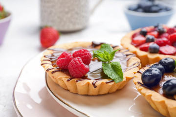 Sweet tartlets with berries on plate, closeup