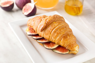 Plate with sweet croissant and fig fruit slices on table