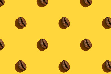 Coffee beans creative pattern on yellow background.