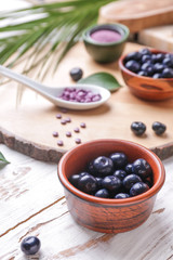 Bowl with fresh acai berries on wooden table