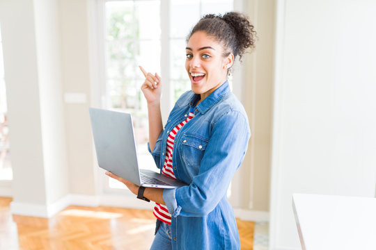 Young african american girl standing working using laptop very happy pointing with hand and finger to the side