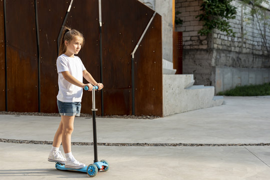 Side view of girl riding blue scooter