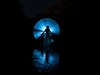 Nocturnal photography, lightpainting, representing a model in the river with shadows made with lanterns on the river