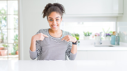Beautiful african american woman with afro hair wearing casual striped sweater looking confident...