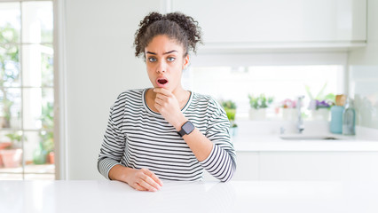 Beautiful african american woman with afro hair wearing casual striped sweater Looking fascinated...