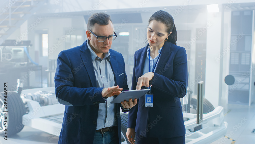Poster female and male engineer work in a high tech development facility holding a tablet computer. they st