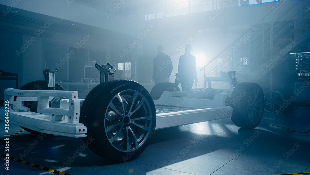 Poster silhouettes of two automobile design engineers in automotive innovation facility. they are working o