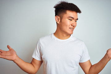 Young asian chinese man wearing t-shirt standing over isolated white background smiling showing both hands open palms, presenting and advertising comparison and balance