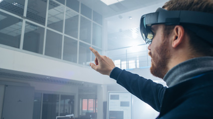 Automotive Engineer Using Augmented Reality Headset and Making Touching Gestures of Virtual Objects...