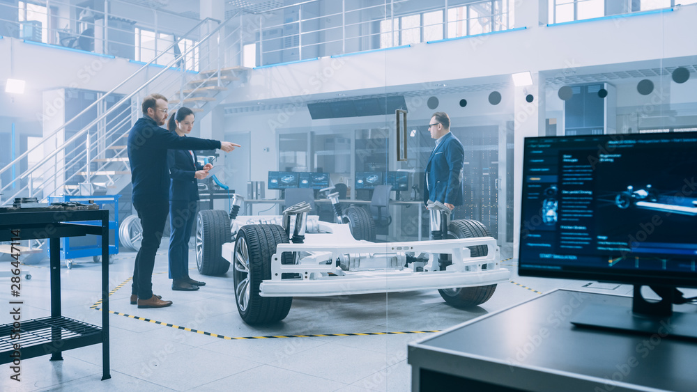 Poster automotive design engineers talking while working on electric car chassis prototype. in innovation l