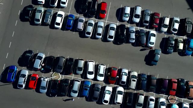 A view from above to the process of car parking. Heavy traffic in the parking lot. Searching for spaces in the busy car park. Parking advice. Cruising for parking in busy business center