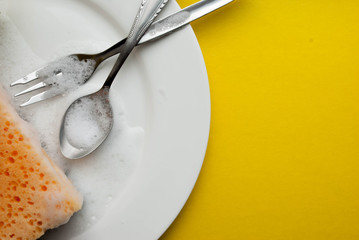 Cleaning sponge on a white plate on a yellow background