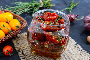 Sun-dried tomatoes with herbs, garlic in olive oil in a glass jar.