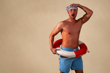 Porträt eines hemdslosen, erschrockenen Mannes,mit Rettungsring und Duschhaube der vor einem beigen Hintergrund steht, Querformat