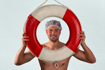 lachender Mann blickt durch einen Rettungsring  mit Duschhaube auf dem Kopf.