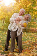 Portrait of happy mature couple posing outdoors in autumn park