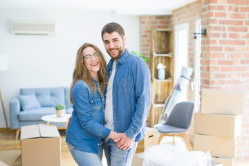 Young couple around cardboard boxes very happy moving to a new home