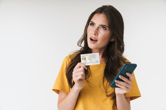 Image of attractive brunette woman wearing casual clothes holding credit card and cellphone