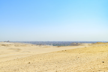 Fototapeta na wymiar Le désert égyptien sous un ciel bleu et la ville du Caire au loin