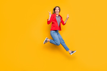 Fototapeta na wymiar Full body photo of lovely girl jumping making v-sign wearing red striped shirt jacket denim jeans isolated over yellow background