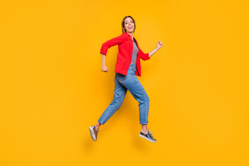 Fototapeta na wymiar Full length photo of pretty person running smiling wearing red striped shirt denim jeans isolated over yellow background