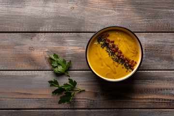 Homemade cream soup with a mixture of beans with red pepper, parsley leaves and black sesame on a wooden background. Top view