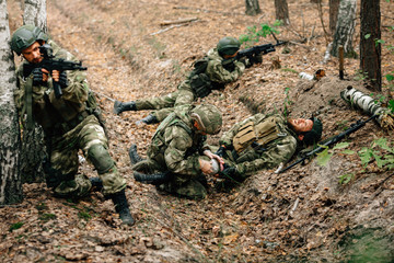 Bandaging a wounded soldier. A group of soldiers in defense of their positions.