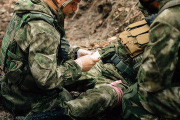 Bandaging a wounded soldier. A group of soldiers in defense of their positions.