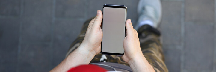 Male hand hold smartphone with blank screen outdoor background