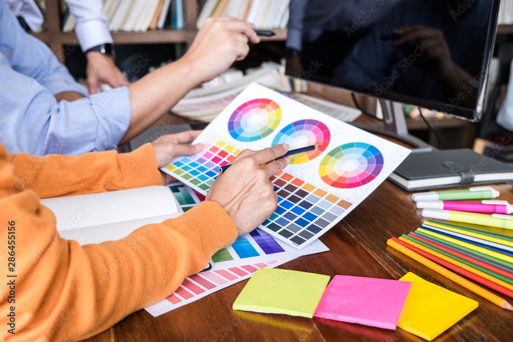 Poster Two colleagues creative graphic designer working on color selection and drawing on graphics tablet at workplace