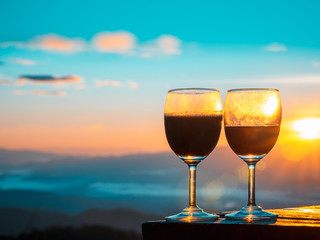 Red wine glass with the sunrise overlooking the mountains background.