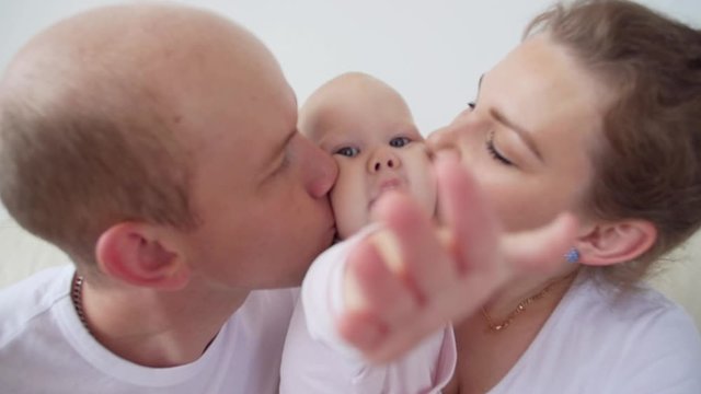 Happy family concept. Parents kissing baby smiling.