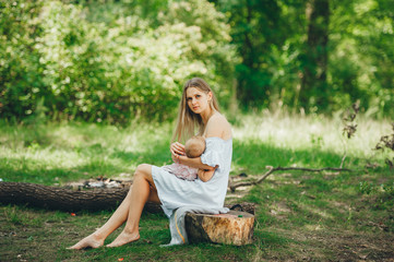 A loving mother breastfeeding her baby in summer forest.