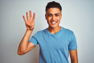 Fototapeta premium Young brazilian man wearing blue t-shirt standing over isolated white background showing and pointing up with fingers number four while smiling confident and happy.