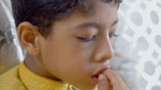 Closeup shot of an innocent Indian boy eating french fries. 