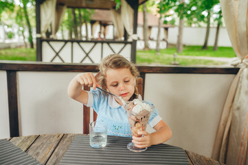 Little girl eat ice cream in cafe outdoors