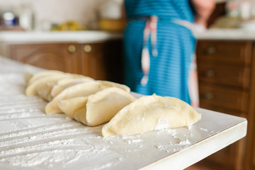 Ready manti, dumplings at the grandmother's kitchen. An old woman is preparing a dish of dough.