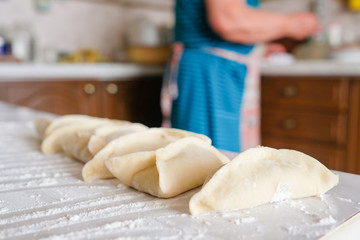 Ready manti, dumplings at the grandmother's kitchen. An old woman is preparing a dish of dough.
