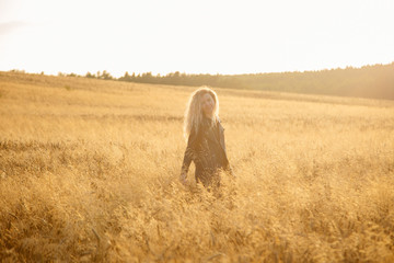 Blonde beautiful girl portrait in the golden field.