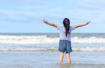 Happy little girl enjoying freedom with open hands on sea,.