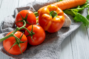 fresh vegetables on a light background. orange carrot, two-tone paprika, red tomato and salad on the kitchen table
