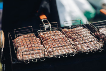 Close-up of delicious chicken or pork sausages on BBQ. Unrecognizable cook preparing tasty sausages on grill.