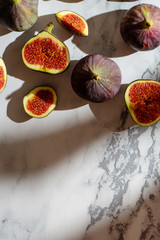 Top view fresh exotic cutted on half fig on marble table. Food photo background. Creative scheme of the whole and sliced figs. Flat lay. View from above. Tasty summer fruit